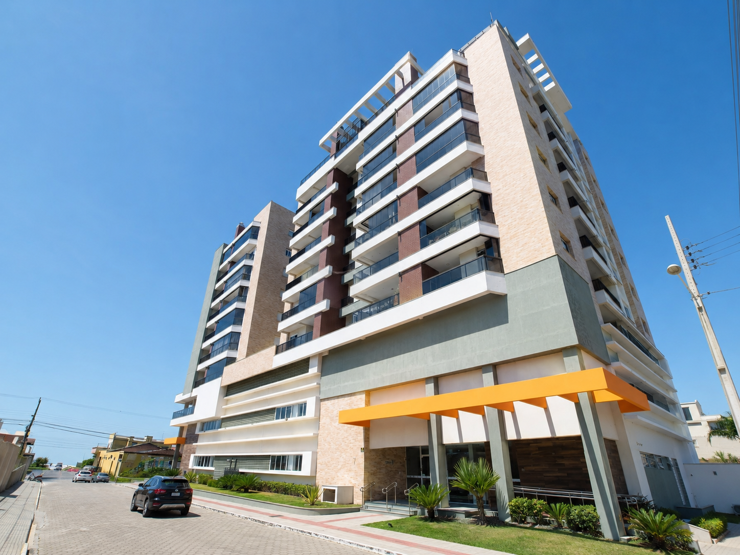 Fachada frontal do edifício em Balneário Arroio do Silva, com entrada social e marquise laranja
