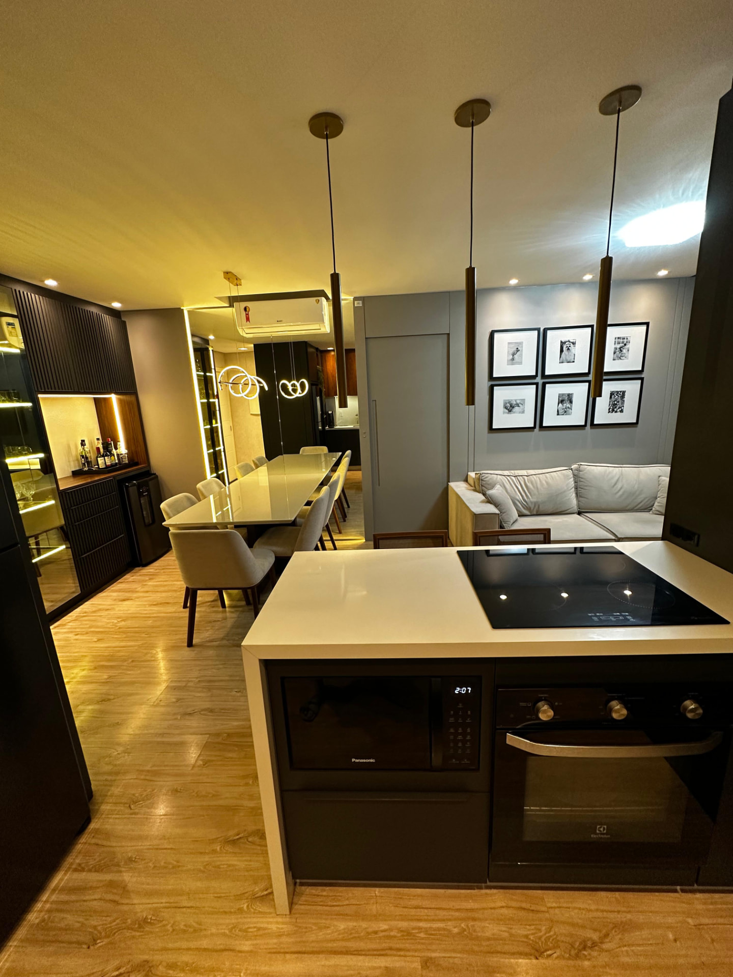 Cozinha com ilha, cooktop, forno e microondas embutidos, integrada à sala de jantar