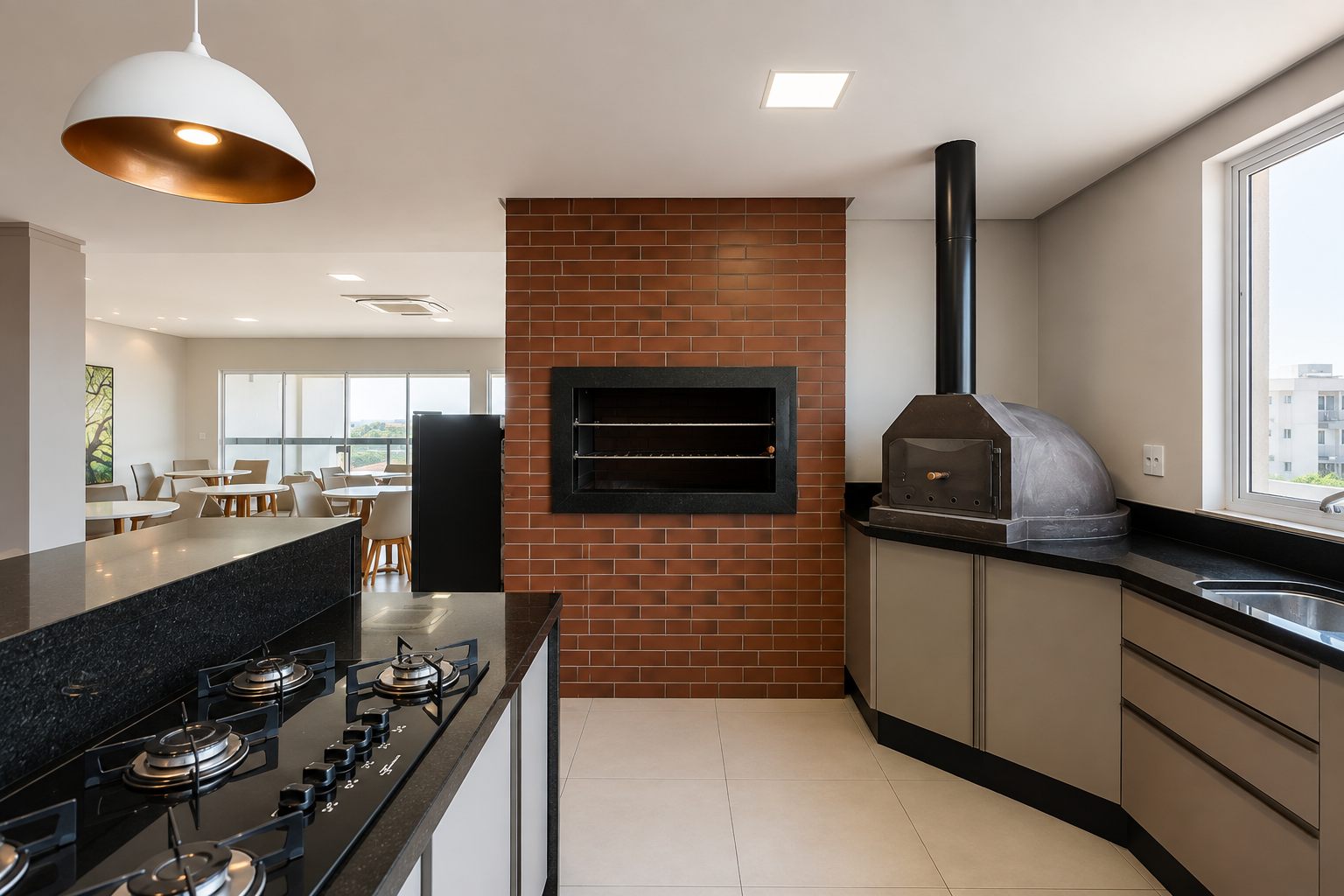 Espaço gourmet do condomínio com churrasqueira, forno de pizza, cooktop e bancada em granito